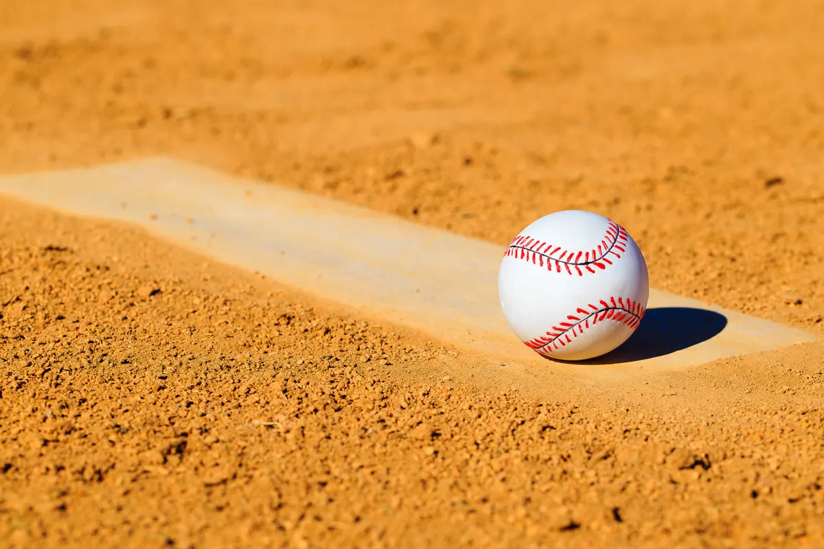 A baseball alone in the dirt.