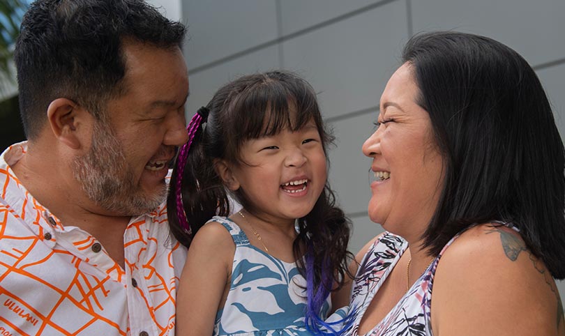 Kalley-Mae laughing in her parents' arms.