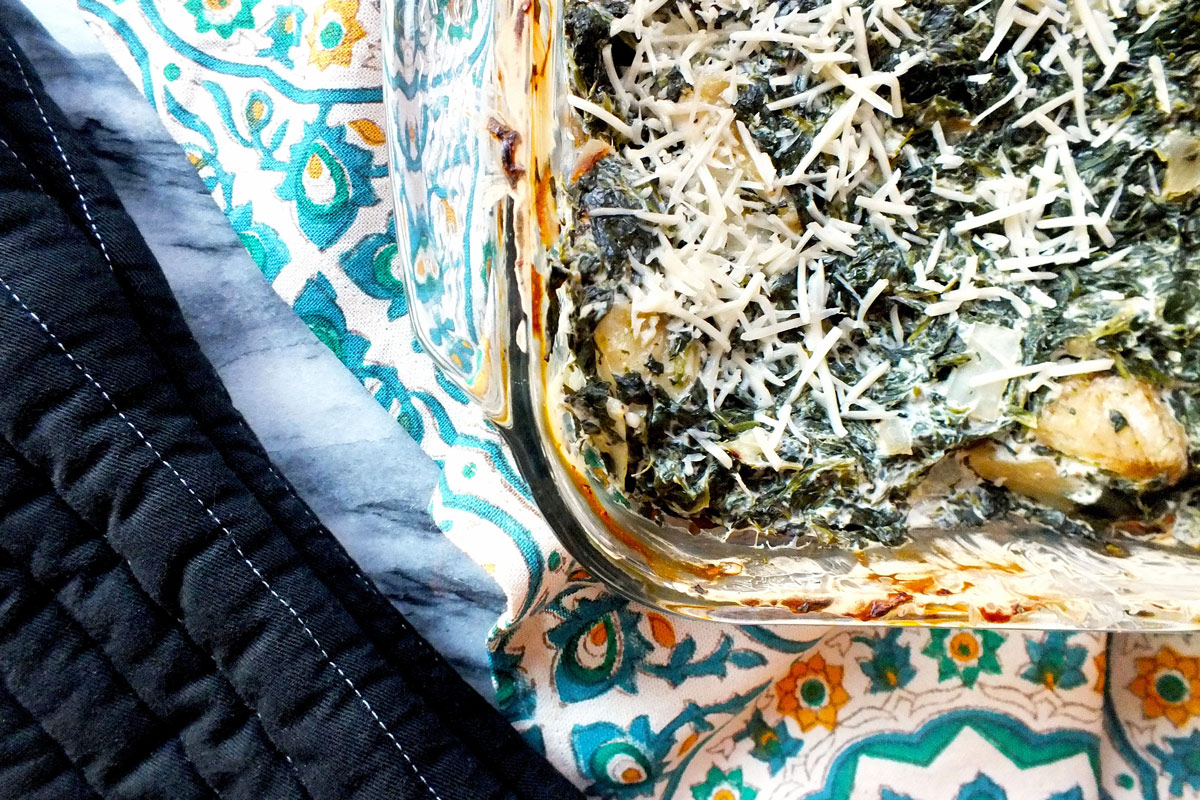 A caserole covered in shredde cheese sits on a table.