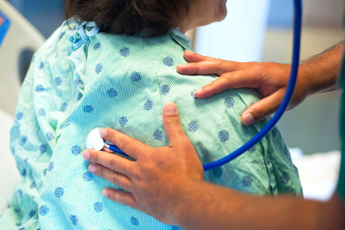 A doctor listening to her patients airways through a stethoscope.