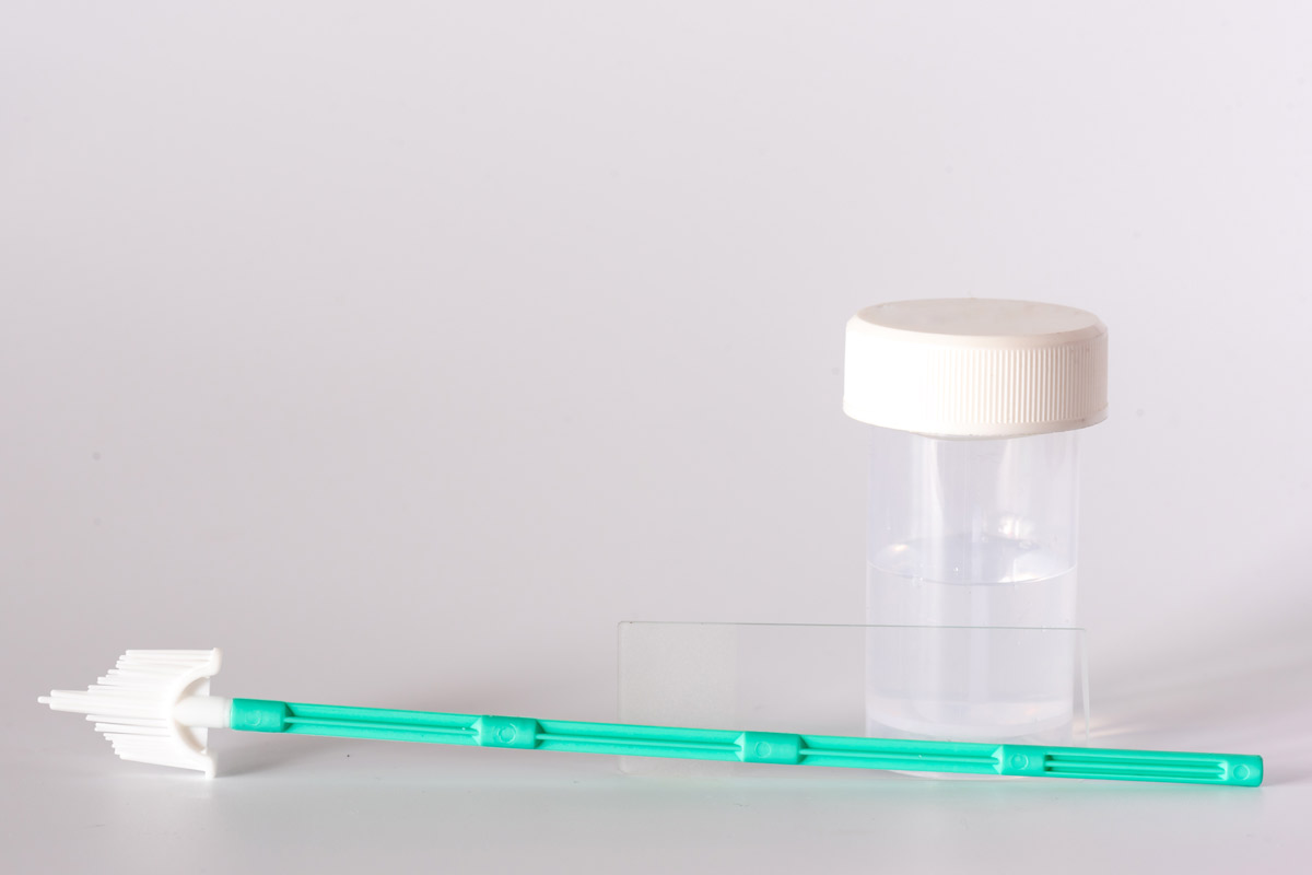 Liquid-based cytology solution bottle, cervical brush and glass slide set on white background.