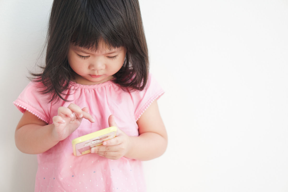 A young toddler playing with games on a cell phone.