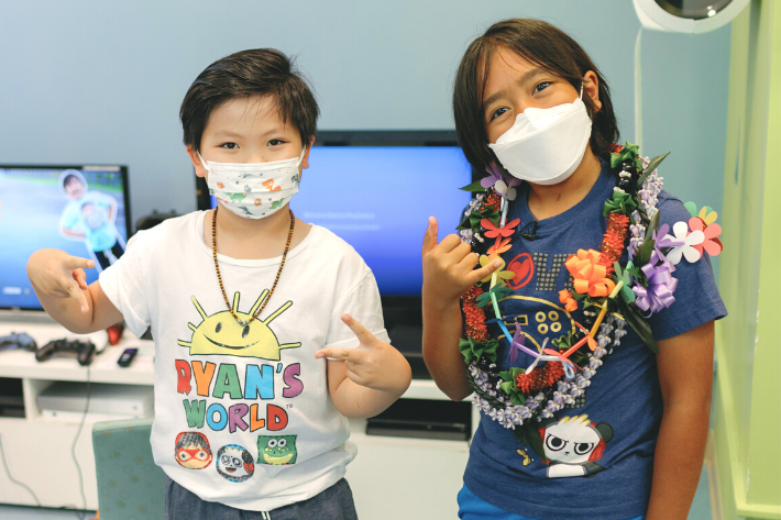 Pediatric patient wearing a Ryanʻs world shirt posing with Ryan Kaji
