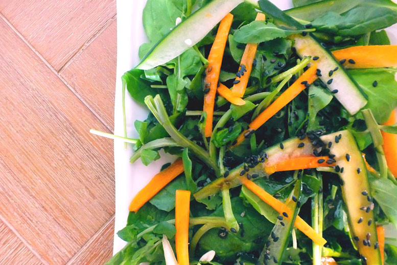 A colorful mix of greens and vegetables with black sesame seed garnish.