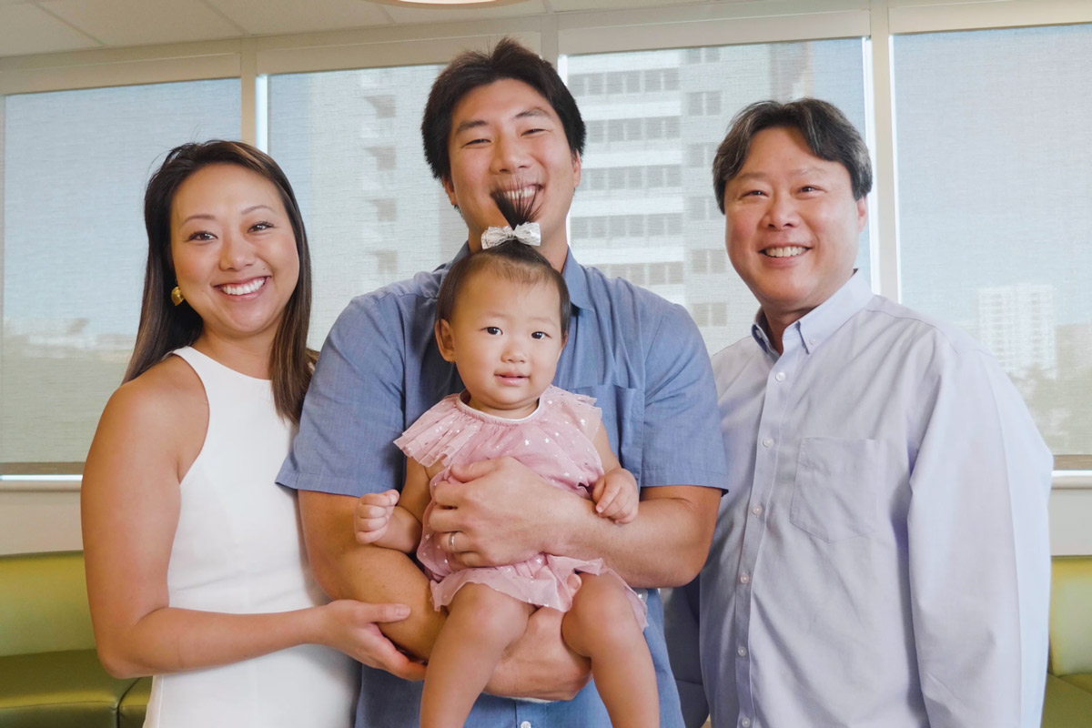 Little girl smiling with her father, mother and grandfather.