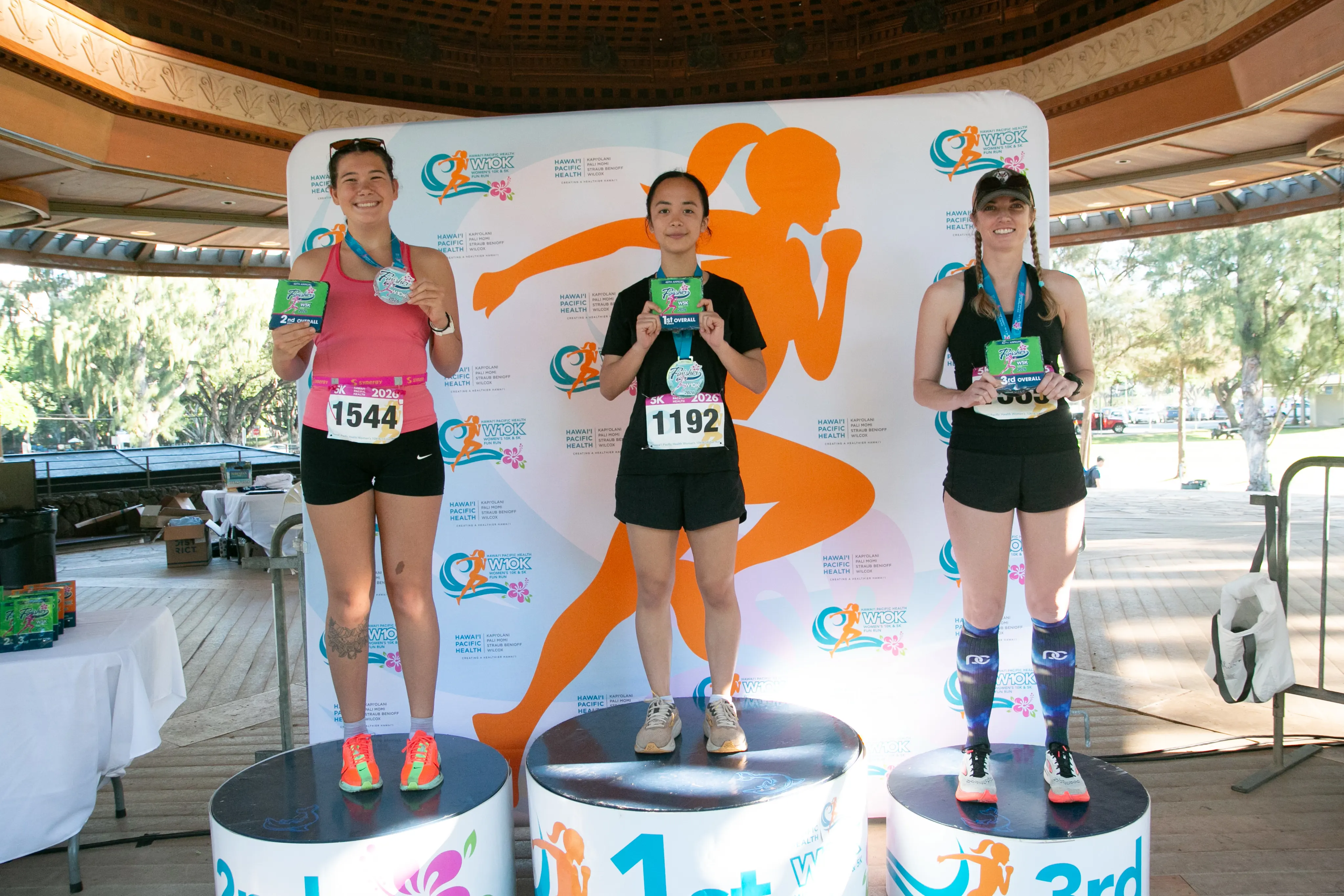 Top three 5K race finishers standing on their respective winner podiums.