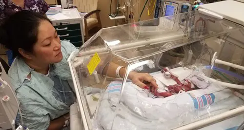 Cherilyn looking at Kalley-Mae's incubator and reaching in to touch her feet.