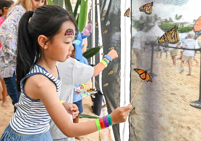 Young girl playing with monarch butterflies.
