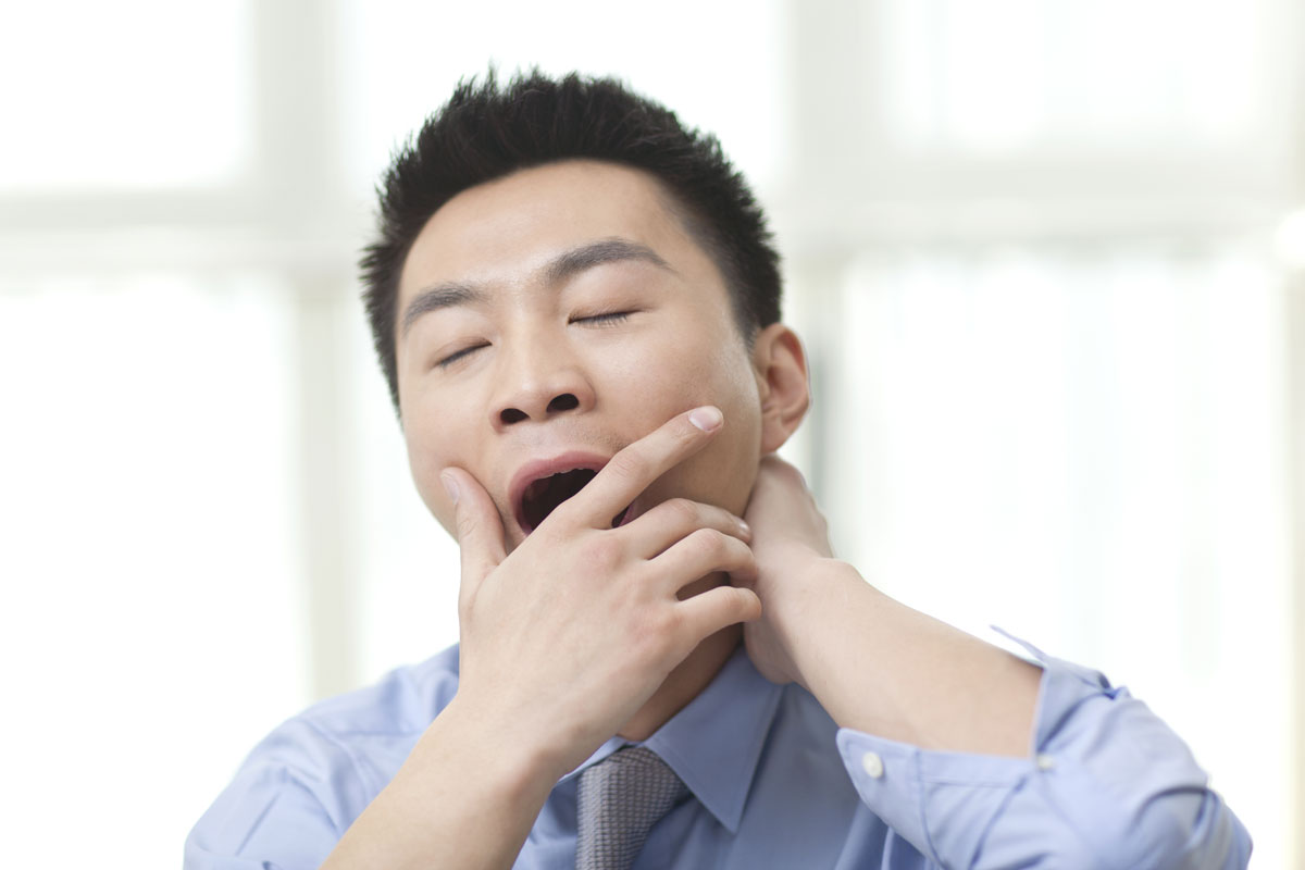 A tired young man yawning.