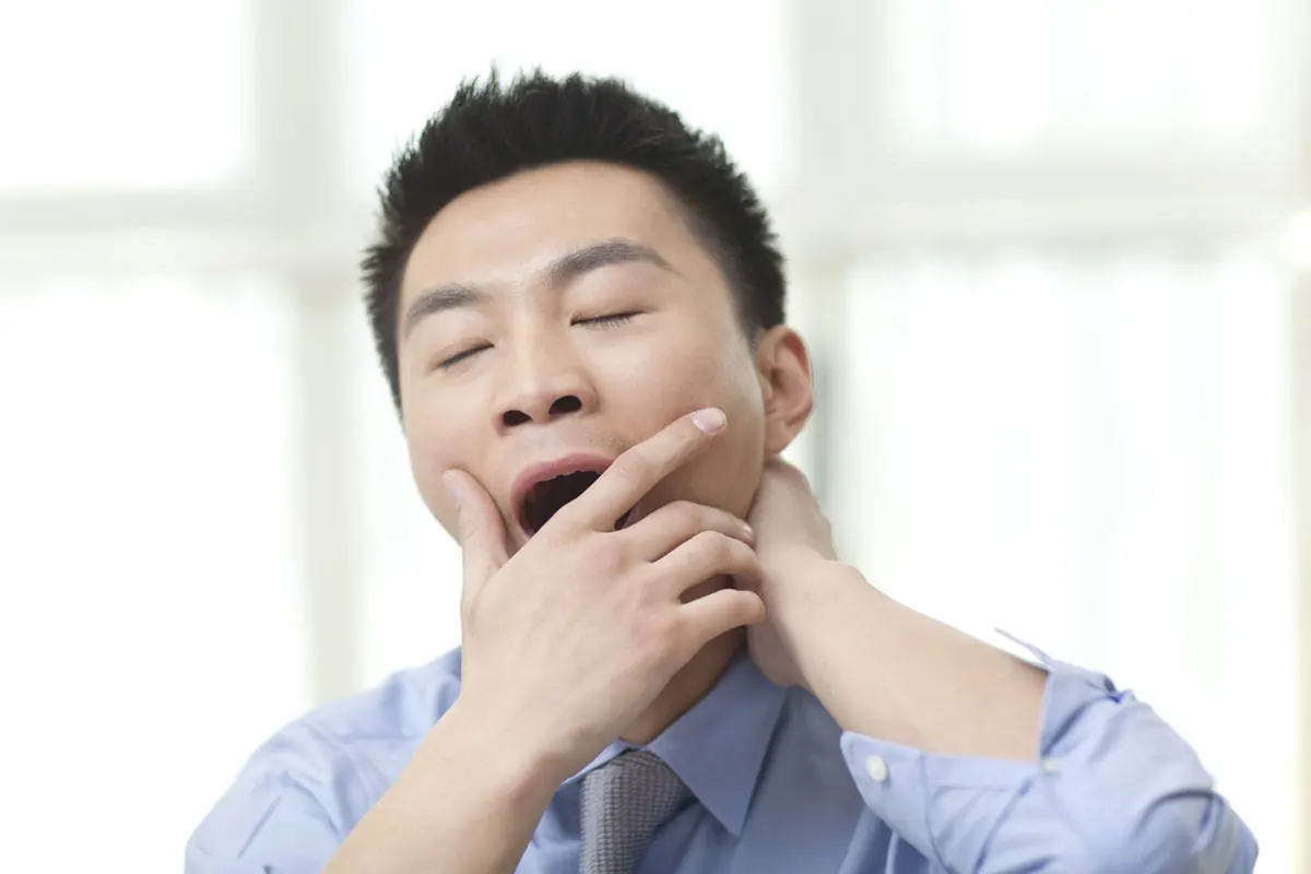 A tired young man yawning.