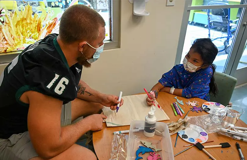Football player coloring with a young Kapiolani patient.
