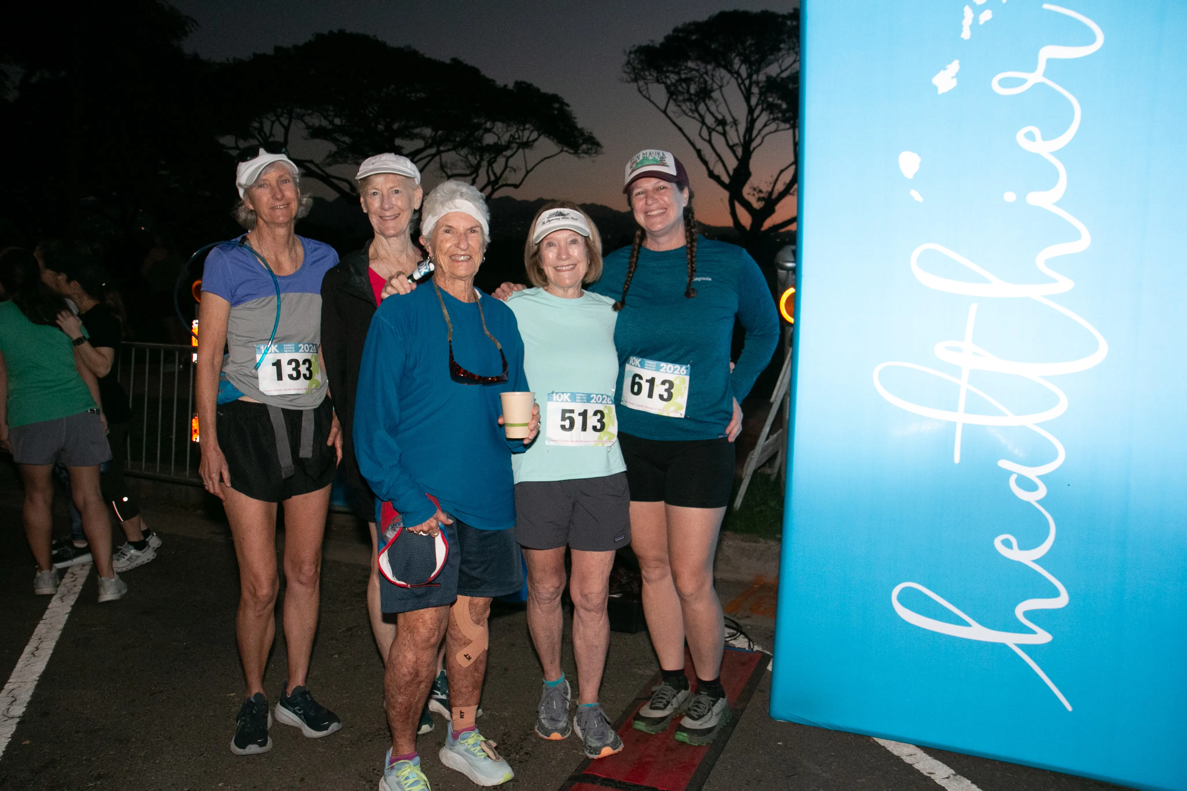 Longtime participants of the race smiling next to the HPH healthier banner. 