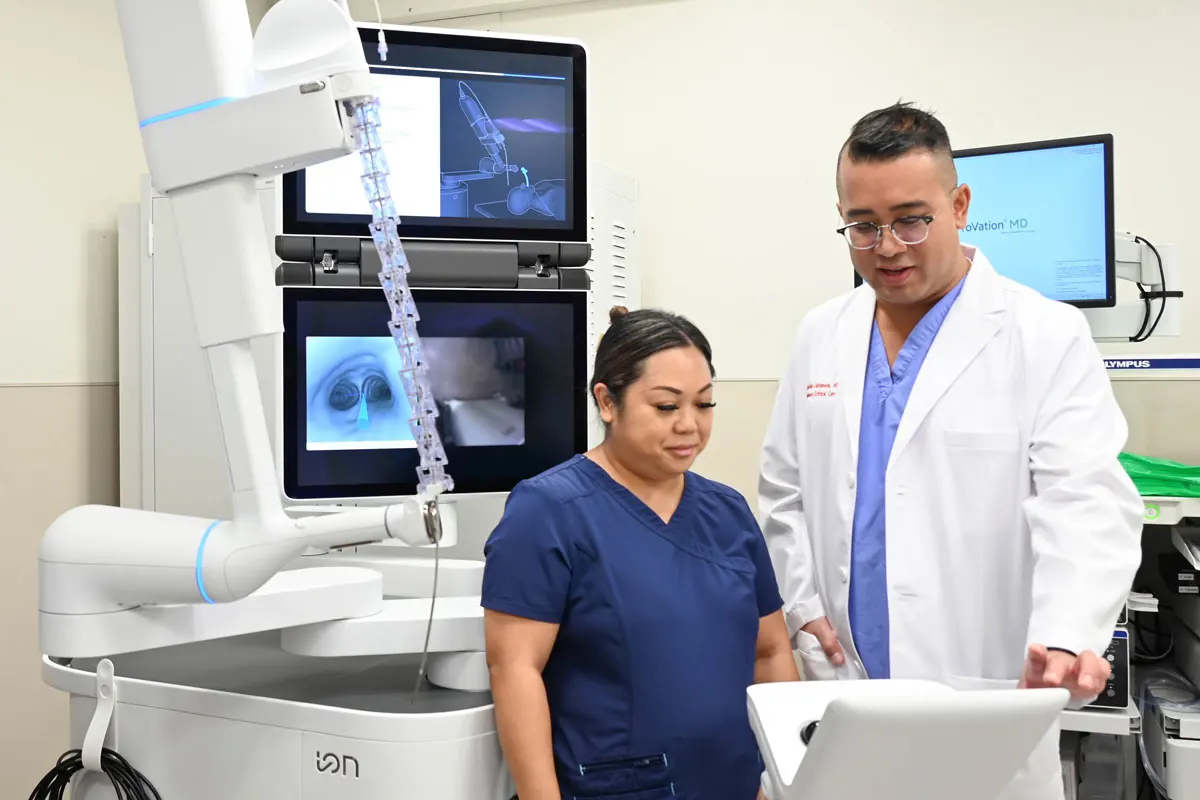 Two medical professionals looking at a screen in an exam room with lots of monitors.