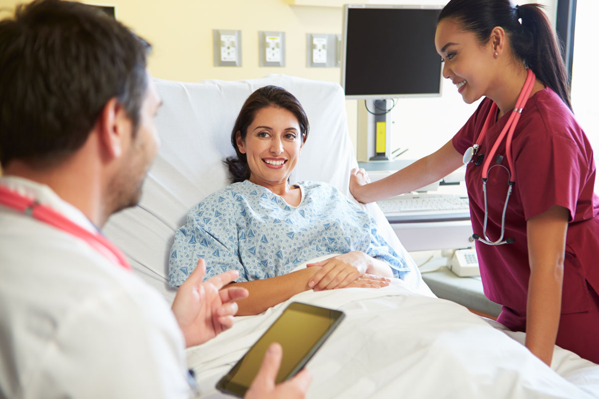 A doctor and nurse discussing treatment options with patient in hospital room.