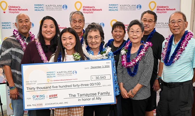 Nine members of the Tamayose family presenting a giant check for $30,543. 