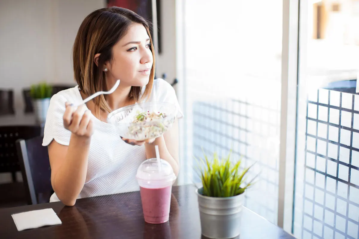 Woman eating a healthy smoothie and salad.