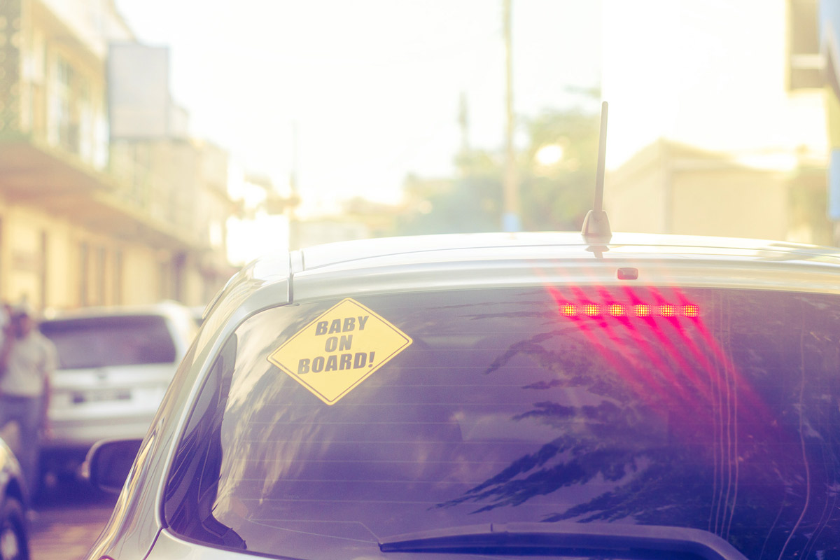 A car windshield with sticker that reads baby onboard.