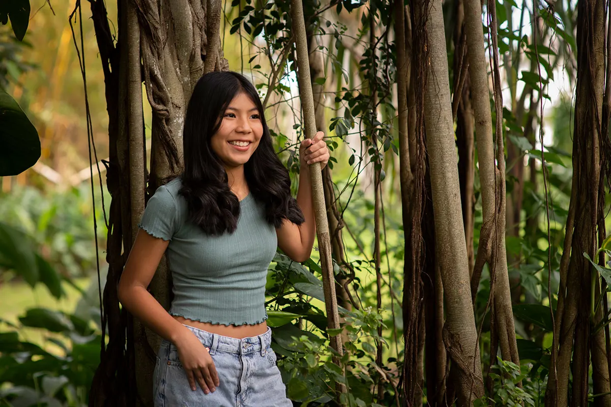 Khloe smiles in a copse of trees.