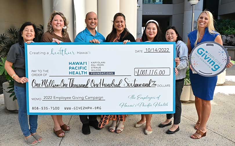 Group of people smiling with a giant check for over $1 million.