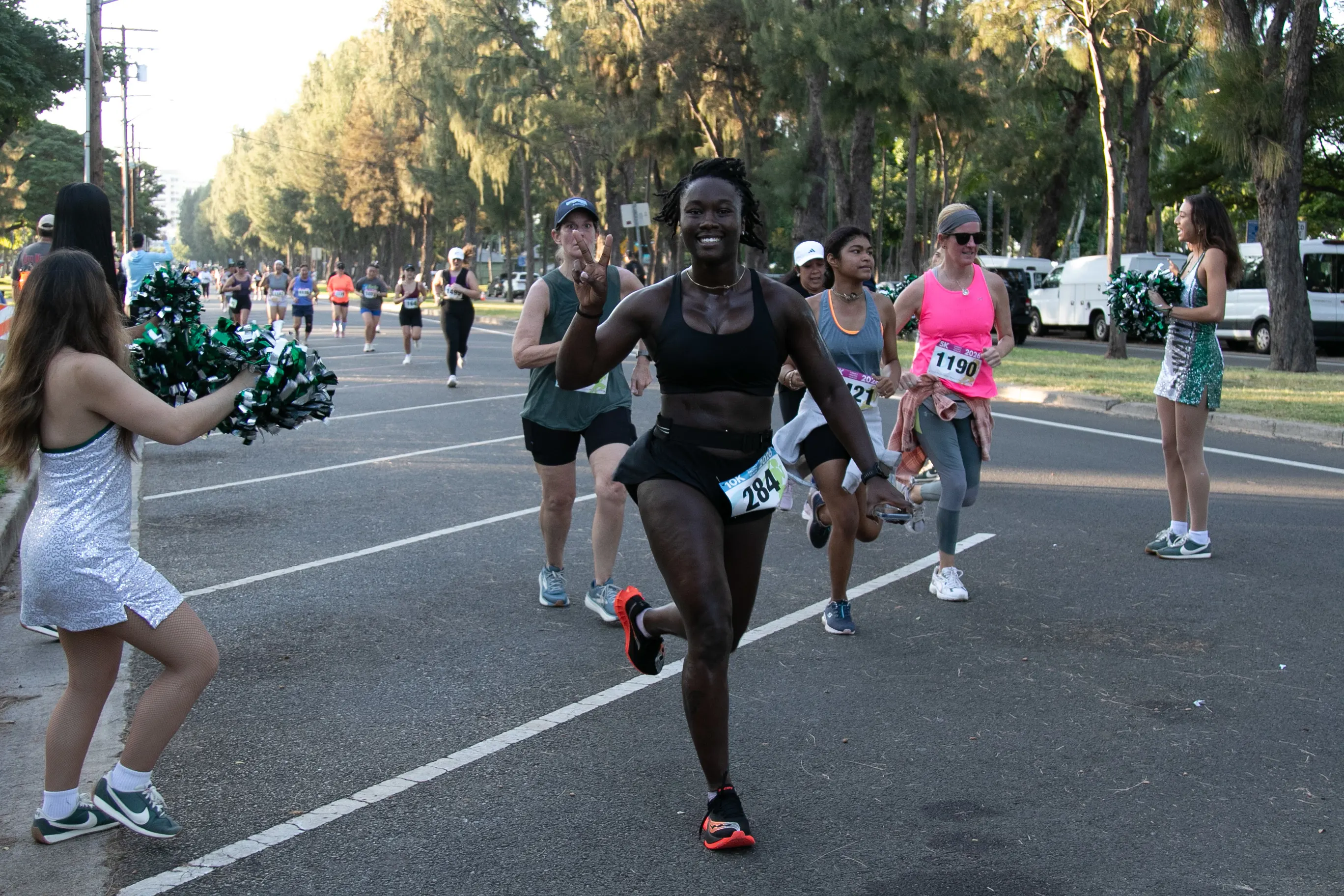 10K participant running toward to the finish line, smiling, and throwing up a peace sign.