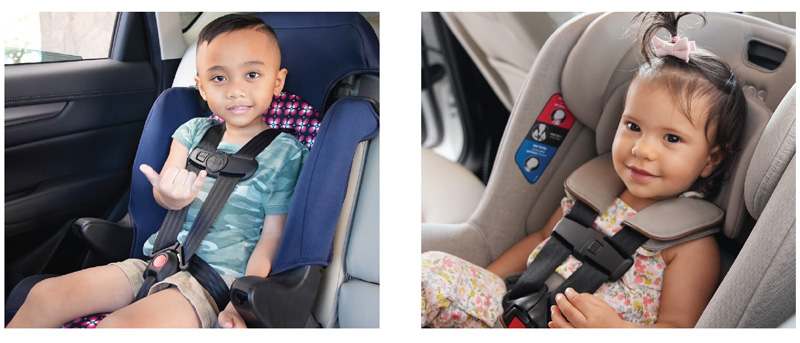 Two children safely sitting in their car seat and smiling.