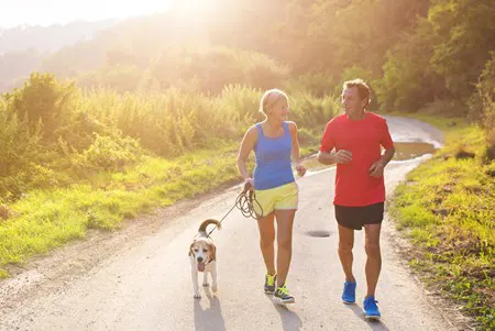 A couple runs with their dog.