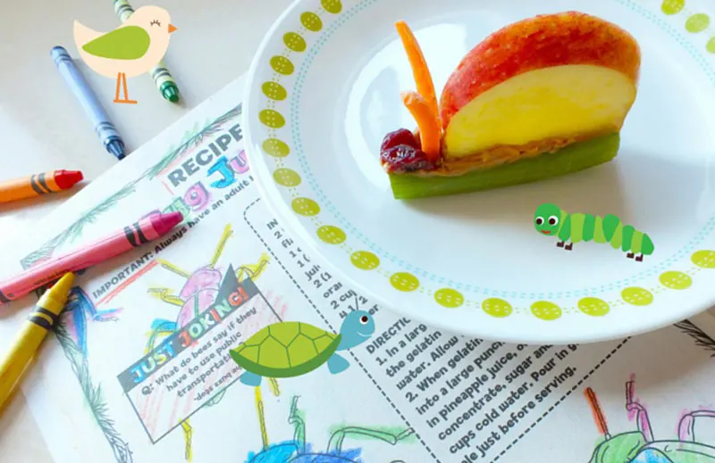 A snail made with a celery piece filled with peanut butter for the base, with raisin eyes, carrot slice antennae, and an apple slice shell.