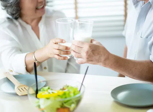 Two people clink their glasses of milk.