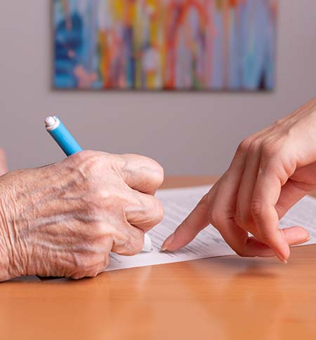 Elder person receiving assistance in signing a document.