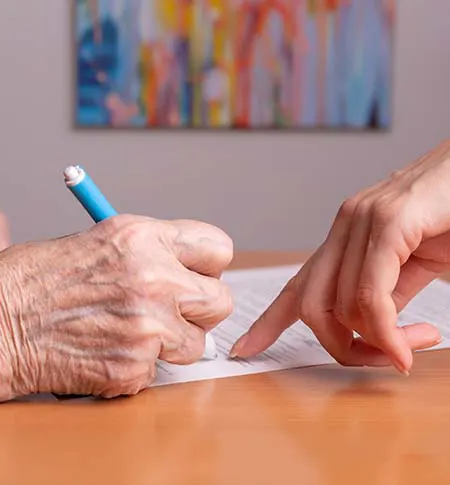 Elder person receiving assistance in signing a document.