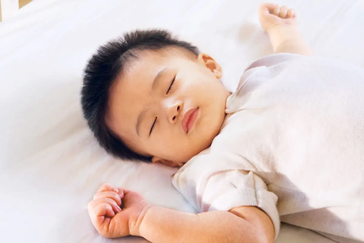 A small child sleeping on their back.