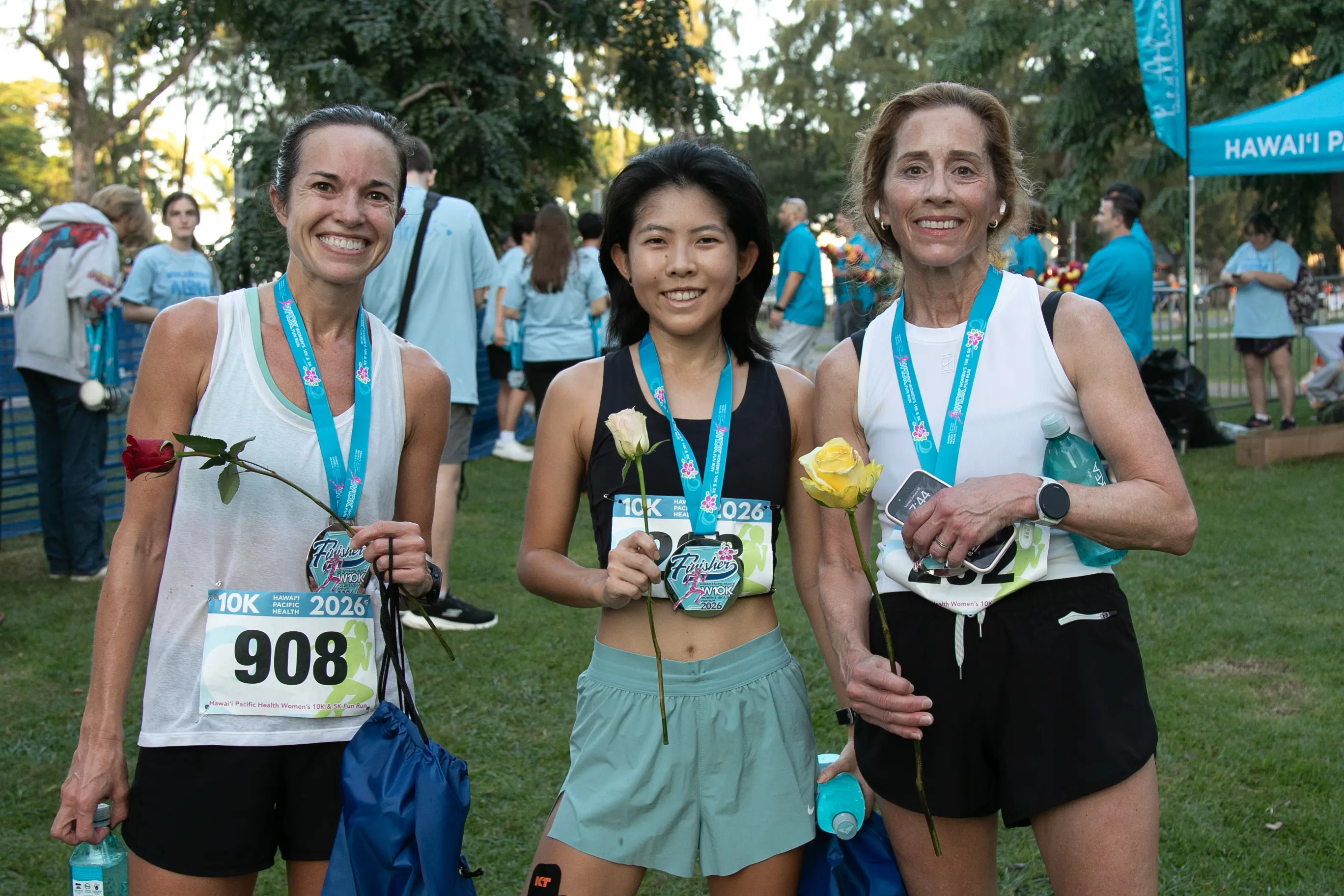 Three 10K finishers wearing their medals and holder their roses.