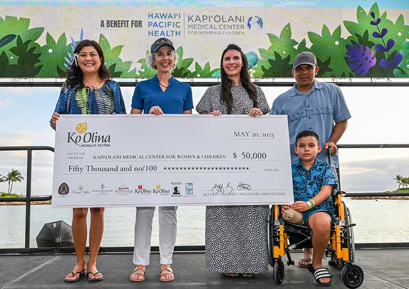 Group standing on a stage with a giant check for $50,000.