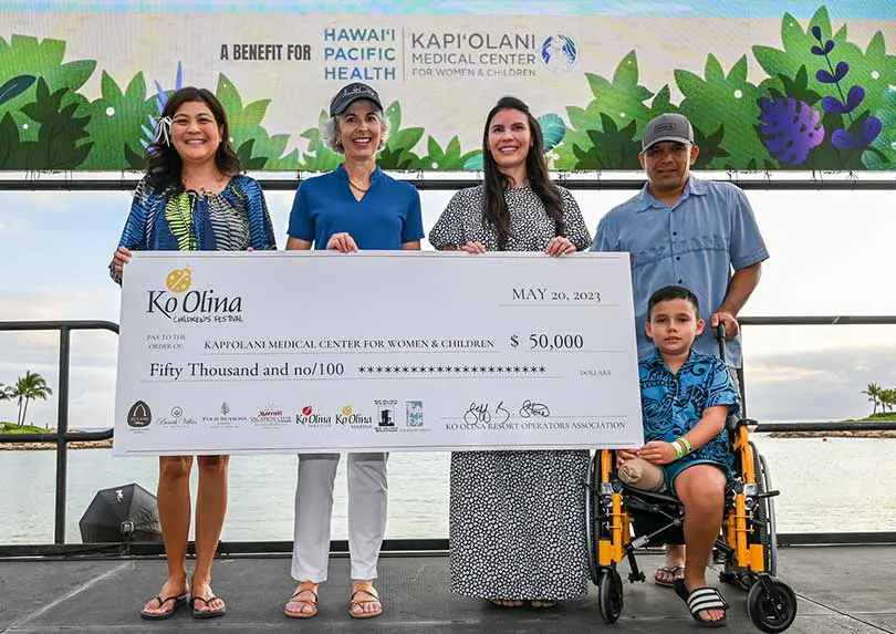 Group standing on a stage with a giant check for $50,000.