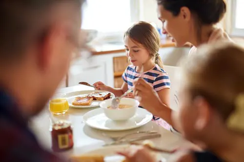 A family sits around a table eating breakfast.