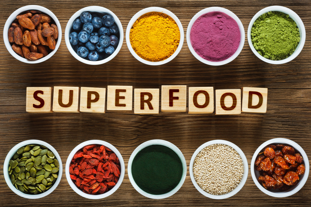 The word "Superfoods" spelled out in blocks surrounded by measuring cups of popular superfoods and supplements.