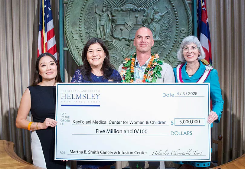 Four people holding a giant check for $5 million in front of the Hawaiʻi state seal.
