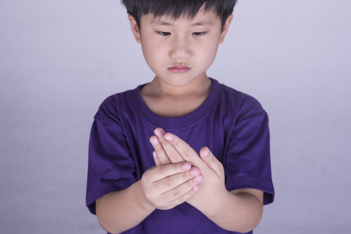 A child clutching sore hand.