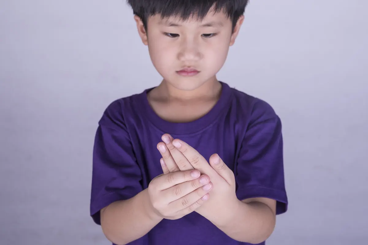 A child clutching sore hand.