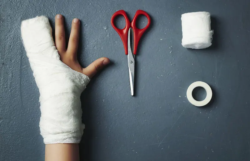 An illustrated injured child hand reaching scissors.