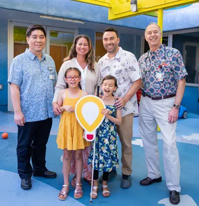 The Awa family with Dr. Glaser and Dr. Sim standing in a blue play area.