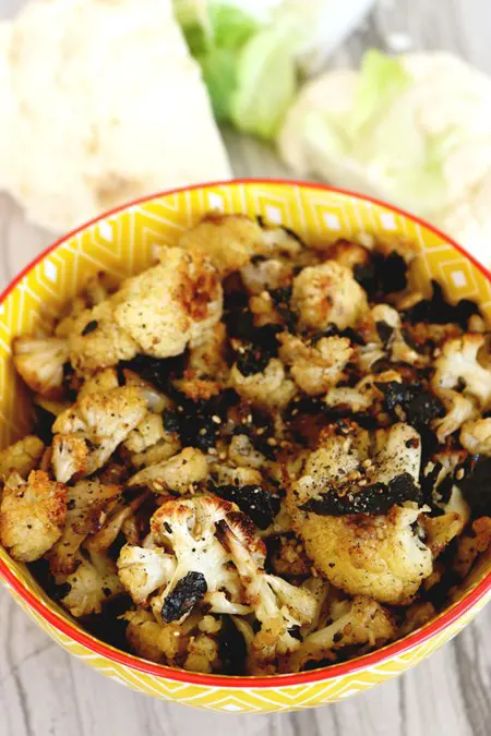 A yellow bowl holds roasted cauliflower dusted with nori.
