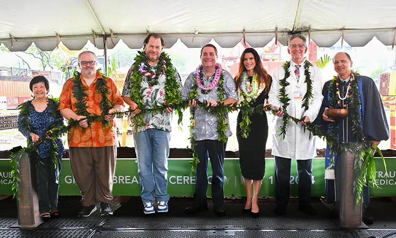 Seven people holding a maile lei as part of a groundbreaking ceremony.