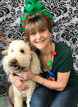 Beeta smiles at the camera in festive holiday decorations with a dog. 