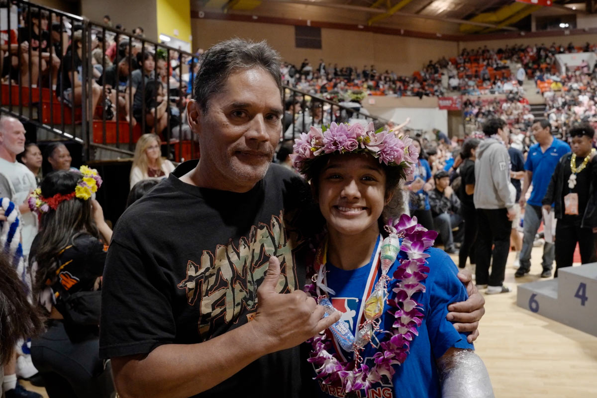 Father celebrating his daughter's success in a wrestling tournament.