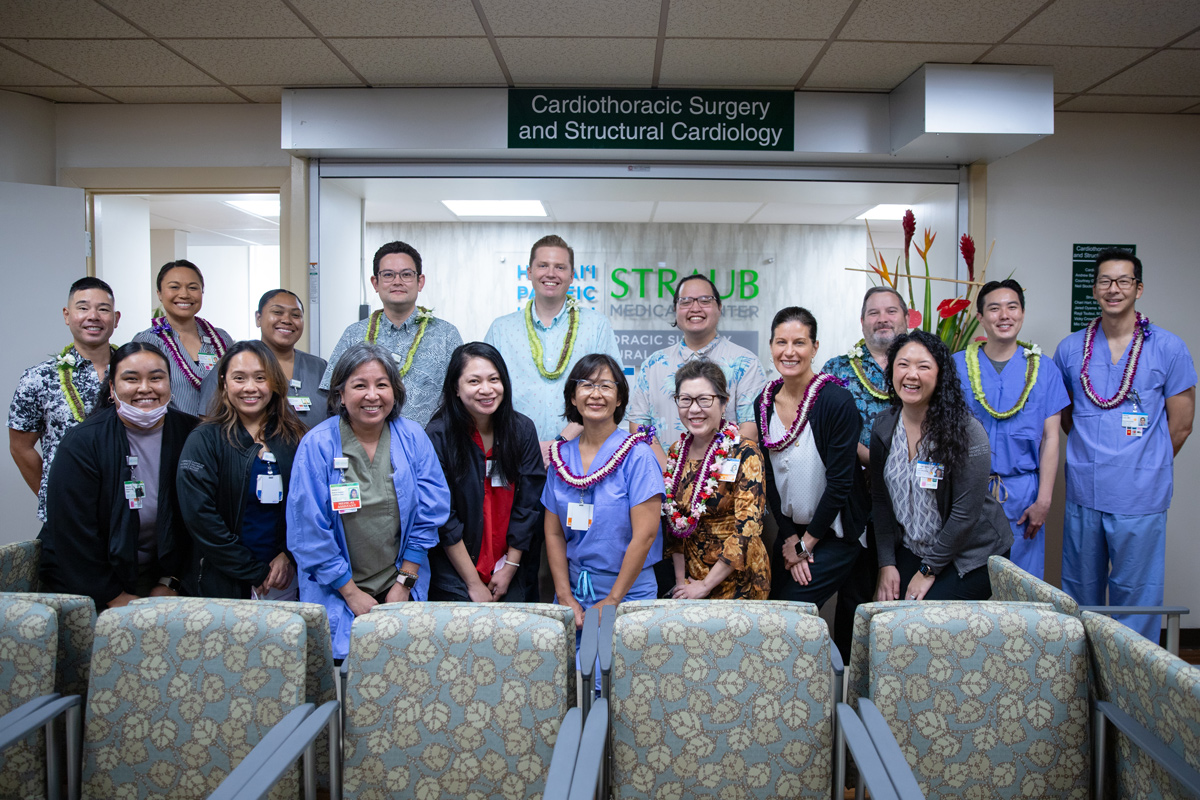 Two rows of medical professionals smile in a cardiology clinic.