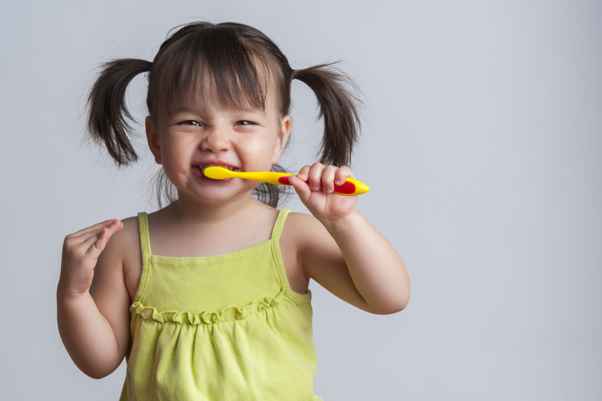 stock image of a little girl with pigtails brushing her teeth.