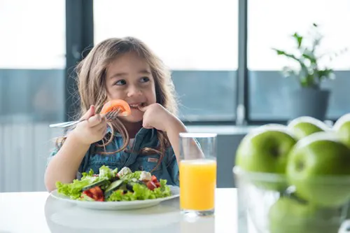 A kid seated at a table eating.
