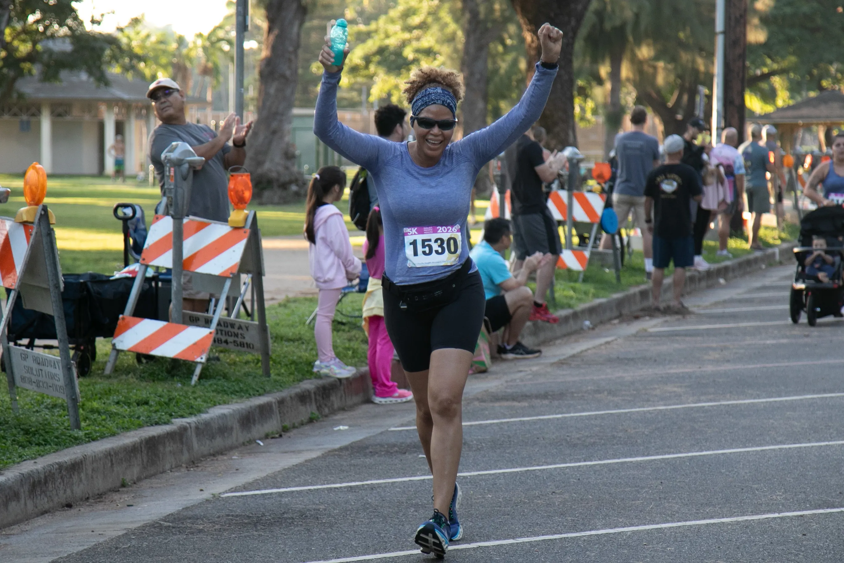 5K participant celebrating with her arms up as she makes her way to the finish line.
