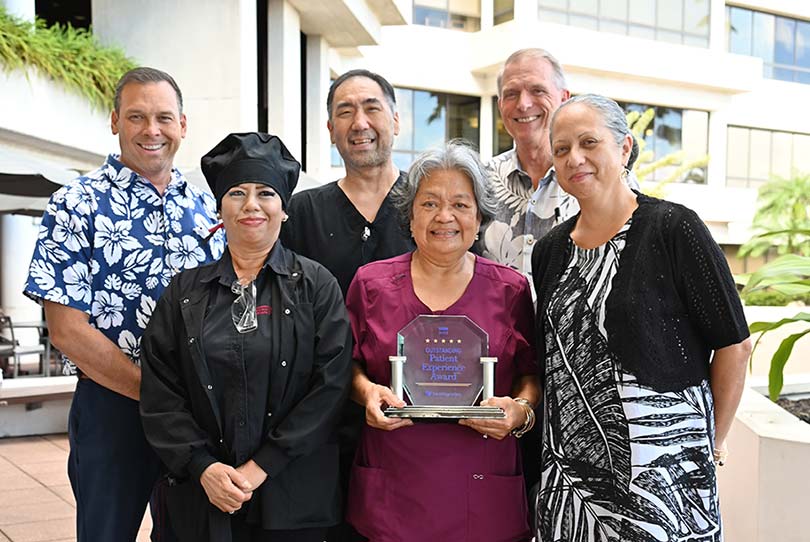 Group of people gathered in front of Pali Momi smiling and posing with an award for Outstanding Patient Experience.